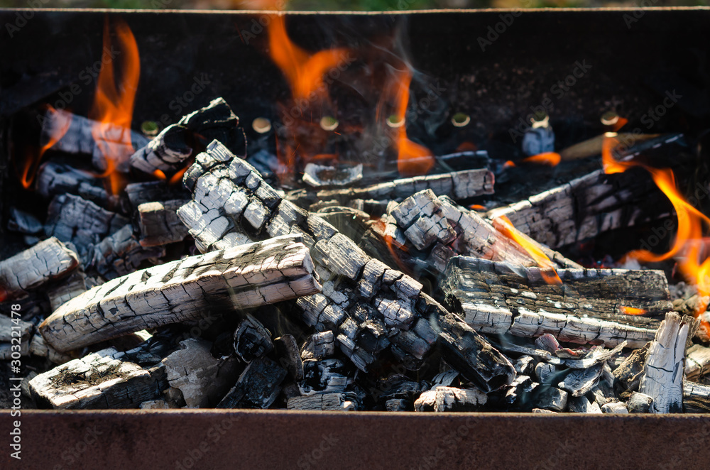 Wood burning and fire in the portable metal grill, fireplace. Fire and charcoal grilled, preparation for barbecue Wood burning and fire in the portable metal grill, fireplace. Fire and charcoal grilled, preparation for barbecue