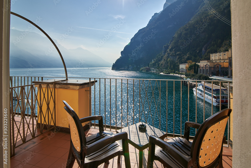 Obraz premium View from the room window of Garda lake surrounded by mountains in the summertime, the port of Riva del Garda and the beautiful Riva del Garda town, , Italy
