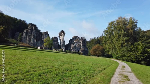 The historic sandstone rocks of Externsteine in East Westphalia in Germany. It is autumn. The sky is blue and the sun is shining. Camera pan.