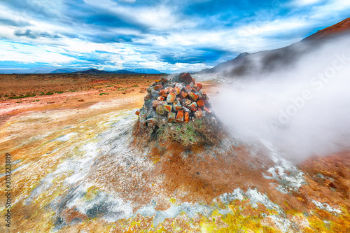 Steaming cone in Hverir geothermal area with boiling mudpools and steaming fumaroles in Iceland