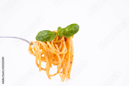 Spaghetti bolognese on a fork on a white background decorated with fresh mint leaves