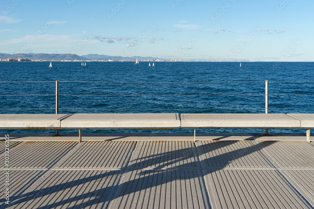 Row of benches looking out to sea on Valencia pier. Shadows on the floor