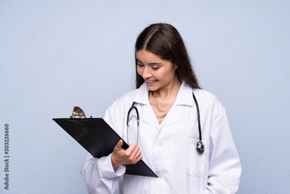 Young woman over isolated blue background with doctor gown and holding a folder Young woman over isolated blue background with doctor gown and holding a folder