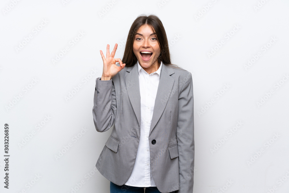 Young business woman over isolated white background surprised and showing ok sign Young business woman over isolated white background surprised and showing ok sign