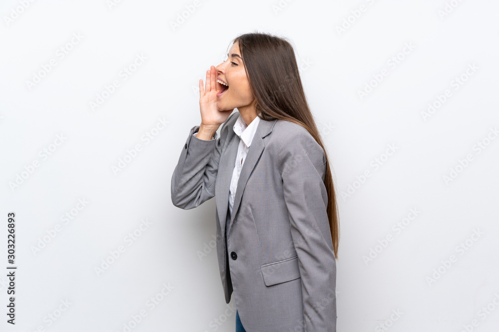 Young business woman over isolated white background shouting with mouth wide open to the lateral Young business woman over isolated white background shouting with mouth wide open to the lateral