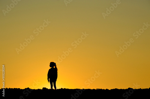 teenager girl posing in a field on a background of golden sunset