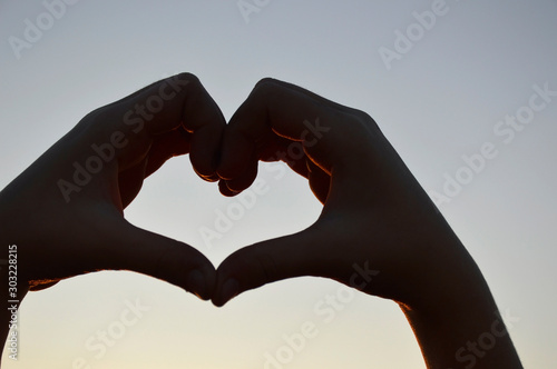 heart made of two hands as a symbol of eternal love against a gray-blue sky