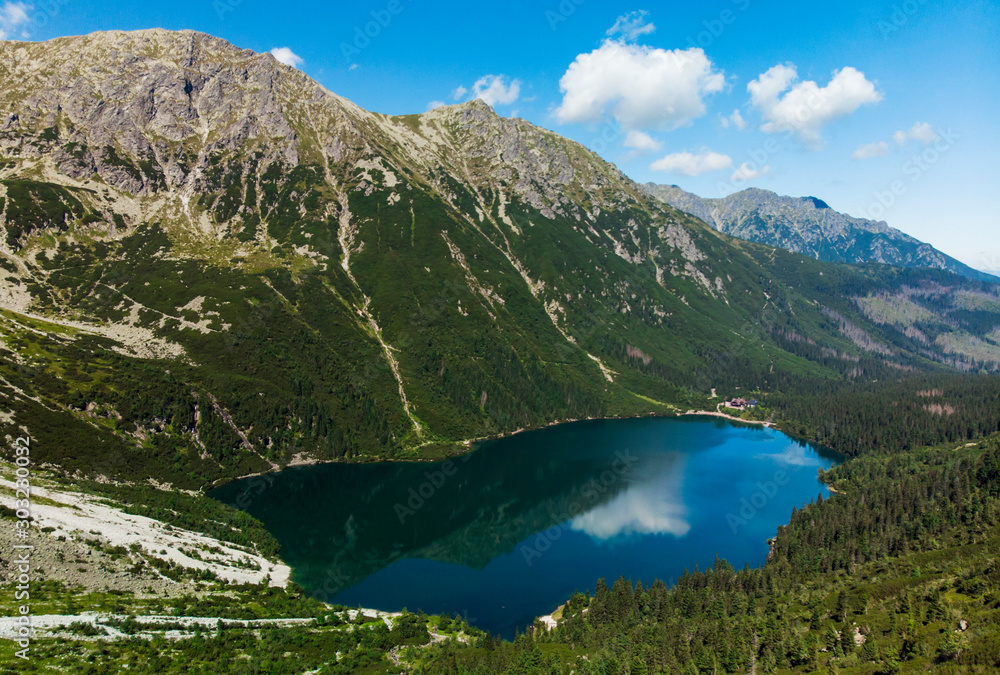 Top of the view of lake Morskie Oko, or Eye of the Sea in Tatra National Park, in southern Poland. Forest green mountain, blue sky, clouds, summer