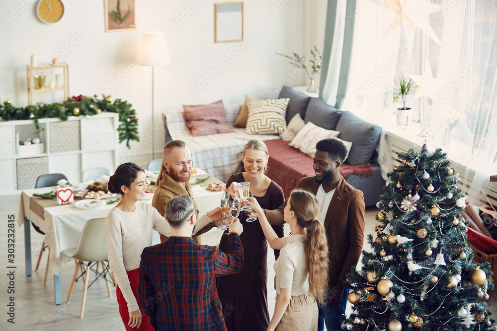 Obraz premium High angle view at group of elegant people enjoying Christmas party and drinking champagne in beautiful dining room, copy space