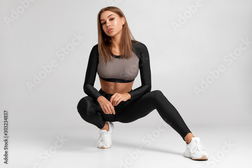 Sexy fitness woman. Beautiful athletic girl on the gray background