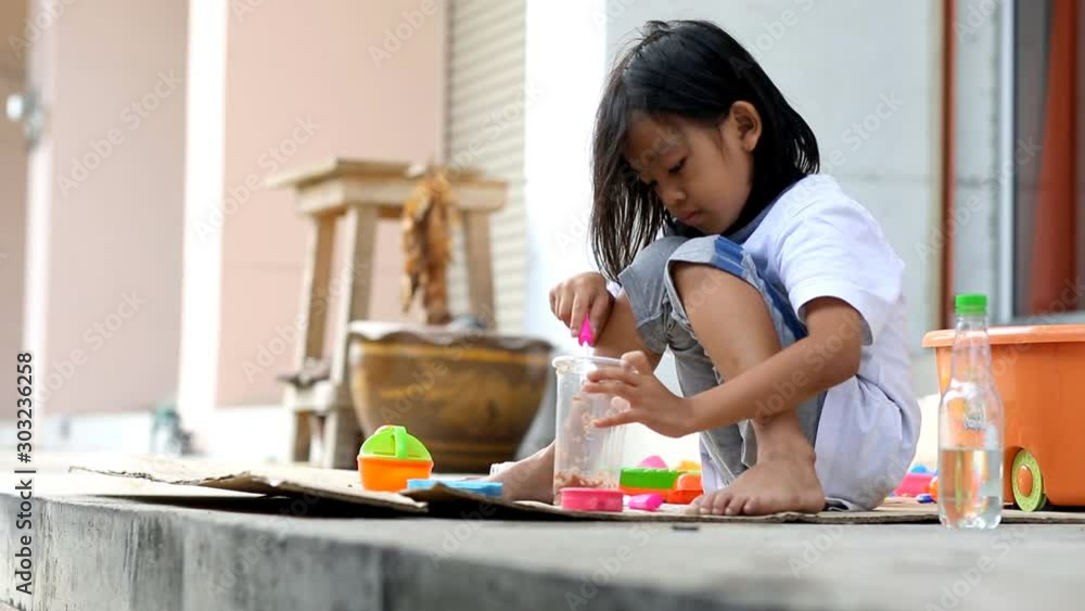 Asian children sit on the floor for playing kitchen toy Asian children sit on the floor for playing kitchen toy