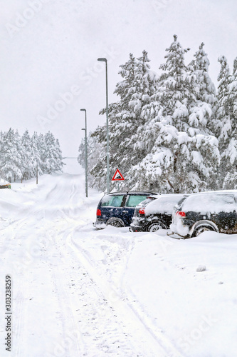 Cars in the parking lot covered in snow during a snowstorm. Image