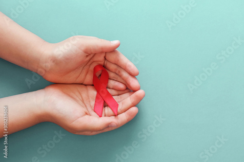 Hands holding red ribbon on blue background, hiv awareness concept, world AIDS day, world hypertension day photo