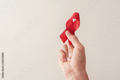Hand holding red ribbon, hiv awareness concept, world AIDS day, world hypertension day photo