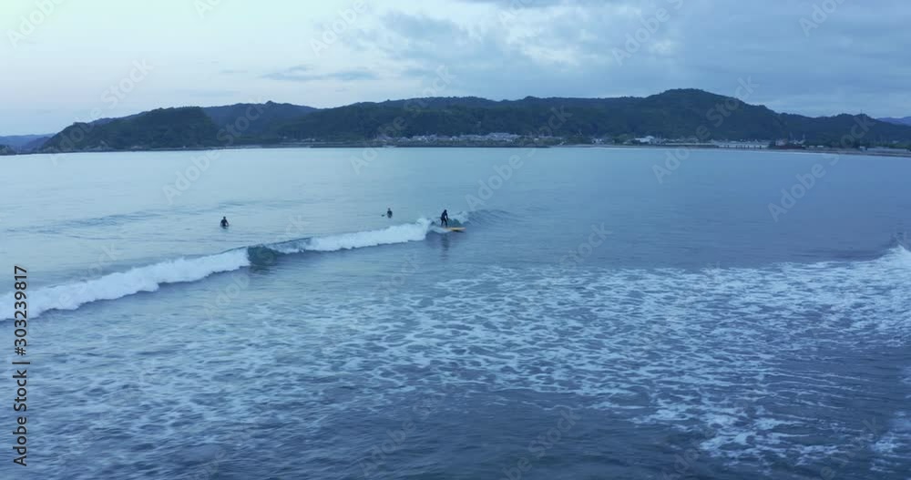Surfers at Shimosato village coastline waves surfing waves at dusk, Wakayama. Aerial tracking right shot above surfer riding wave on surfboard. Surfers at Shimosato village coastline waves surfing waves at dusk, Wakayama. Aerial tracking right shot above surfer riding wave on surfboard.