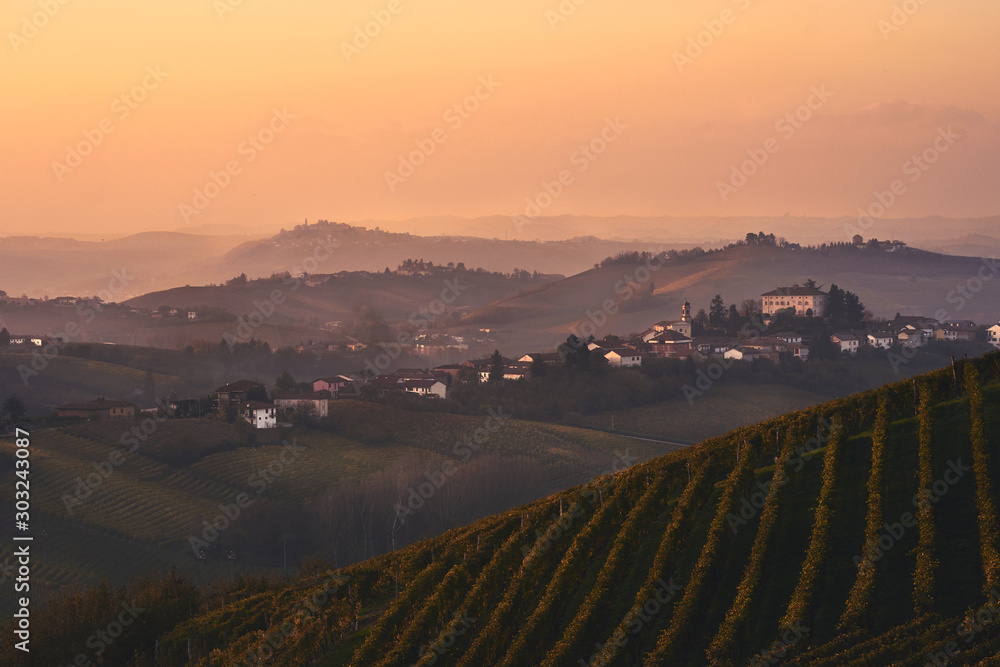 beautiful Italian landscape -evening over Piemonte hills with vineyards with little village on the top of the hill