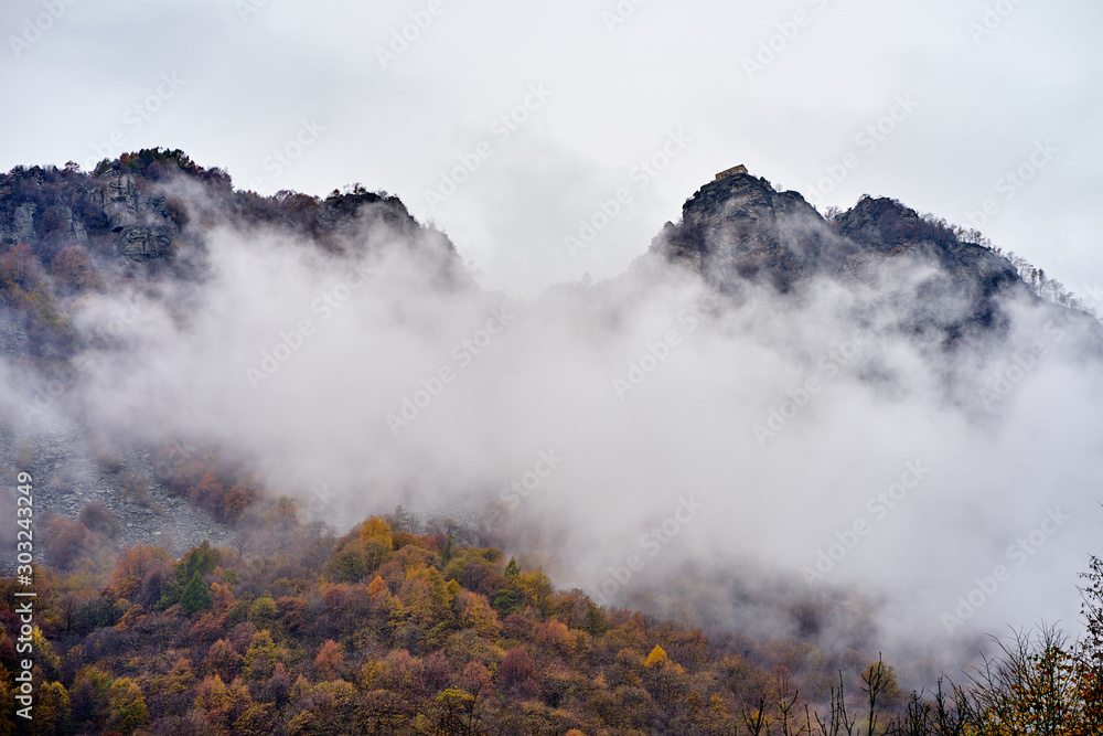 two rocks covered by clouds and a fog in Italian Piemonte