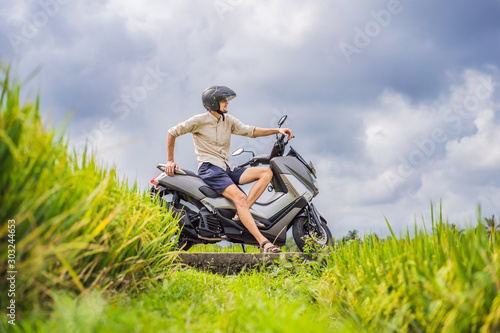 Male traveler on a bike among a rice field. Tourist travels to Bali © galitskaya