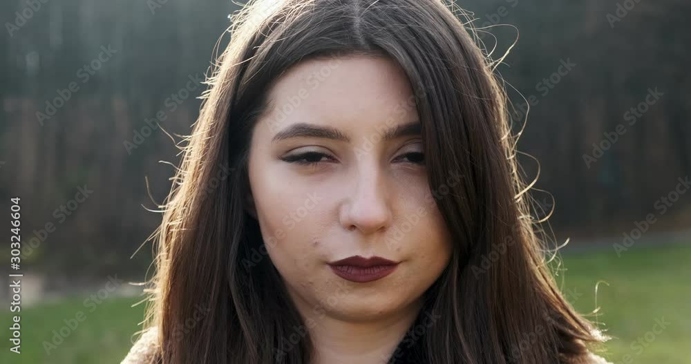 Portrait of young attractive female who smiling and looking at the camera on green lawn. Cheerfully pretty woman. Close up Portrait of young attractive female who smiling and looking at the camera on green lawn. Cheerfully pretty woman. Close up