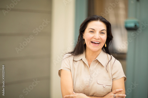 Happy Hispanic woman smiling and standing outside.