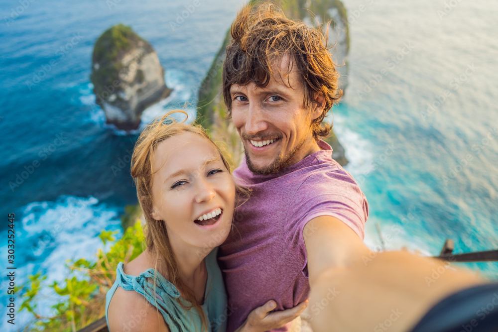 Family vacation lifestyle. Happy couple - man and woman stand at viewpoint. Look at beautiful beach under high cliff. Travel destination in Bali. Popular place to visit on Nusa Penida island