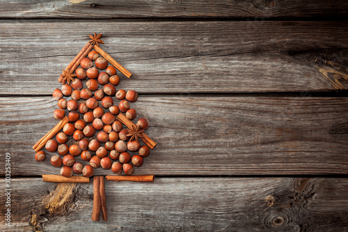 Christmas tree made of nuts and spices on old wooden background. Winter background
