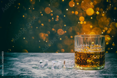 Whiskey and ice on a golden bokeh background for Happy Day.