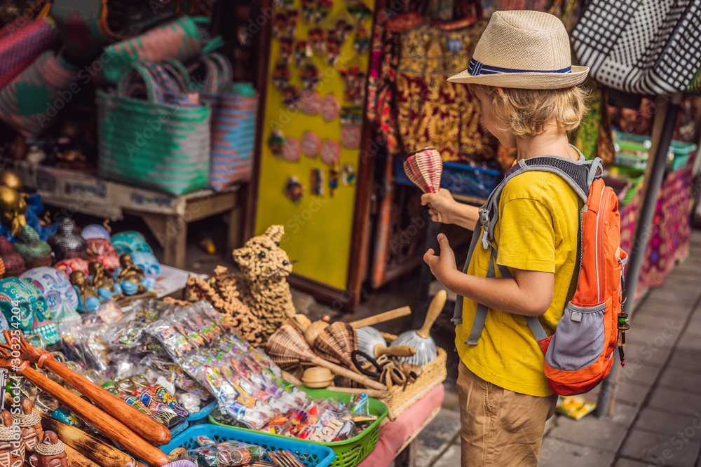 Boy at a market in Ubud, Bali. Typical souvenir shop selling souvenirs and handicrafts of Bali at the famous Ubud Market, Indonesia. Balinese market. Souvenirs of wood and crafts of local residents