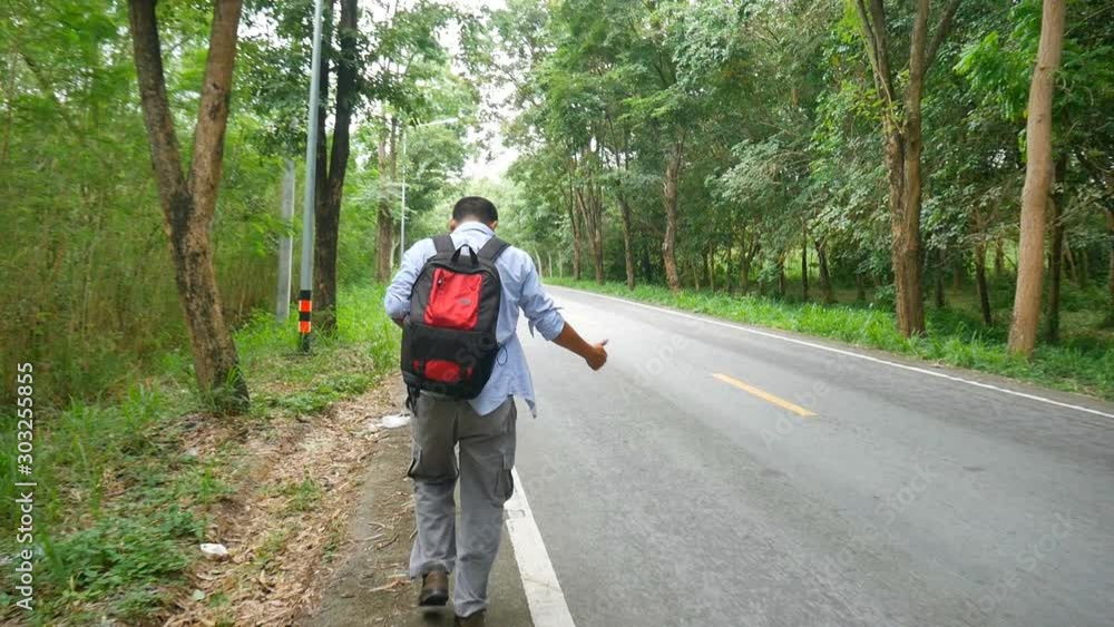 Man backpacker walking alone on the country road Man backpacker walking alone on the country road
