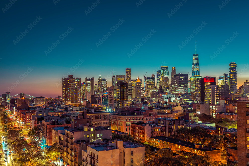 Fototapeta premium Wieżowce na Dolnym Manhattanie o zachodzie słońca. Ulica z samochodami i mostem Brooklin na horyzoncie, Nowy Jork