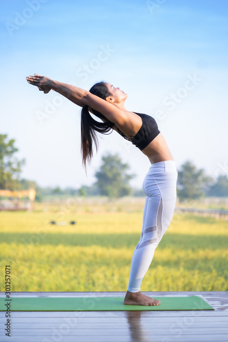 Young Asian playing and pose Yoga on the floor with nature rice field and blue sky background, Yoga Concept.