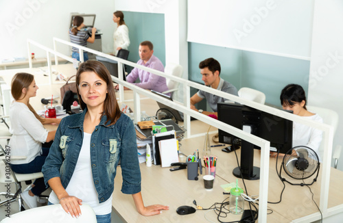 Smiling female manager standing in open space office during working process