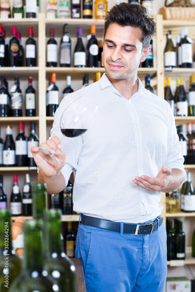 Glad man holding glass of red wine in winery section
