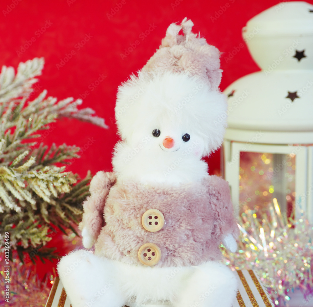 Cute toy snowman, spruce branches, tinsel and a candlestick on a red background....