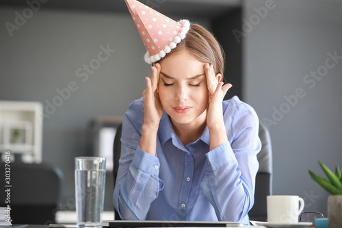 Obraz na plátně Young woman suffering from hangover in office