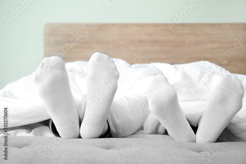 Feet of young couple sleeping in bed