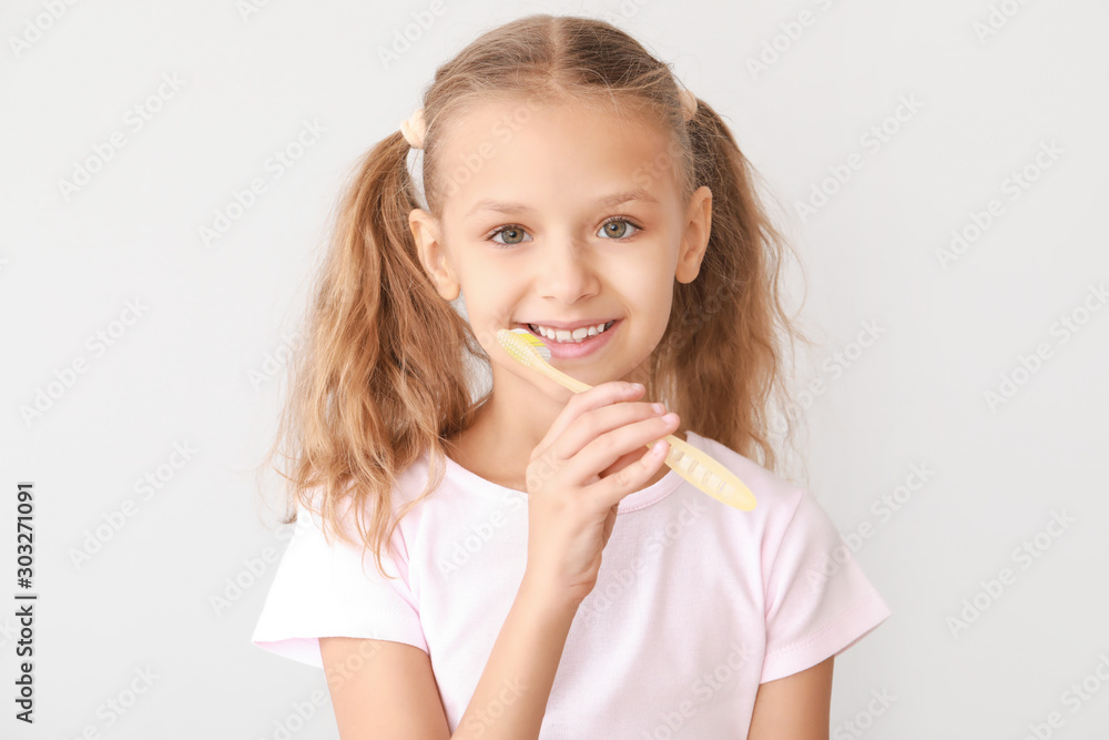 Portrait of little girl brushing teeth on light background Portrait of little girl brushing teeth on light background