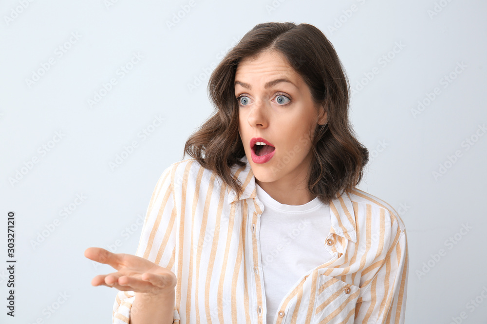 Surprised young woman on light background Surprised young woman on light background