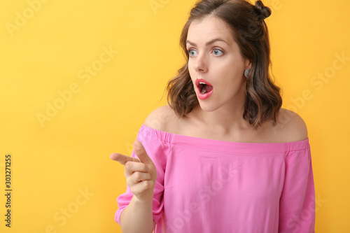 Surprised young woman point...