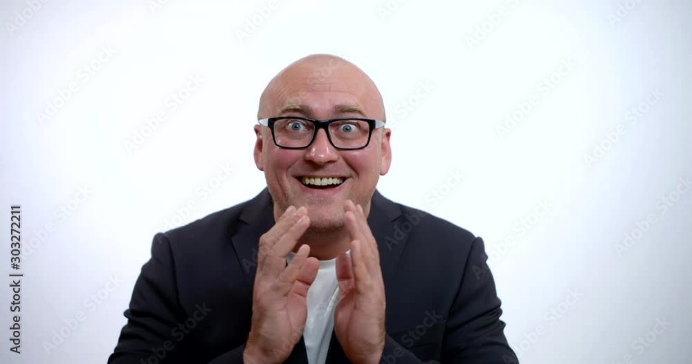 A portrait of a crazy bald man with glasses, wearing a jacket and a white shirt, he is in the Studio on a white background, smiling, bringing his hands together, looking up and clenching his fists. A portrait of a crazy bald man with glasses, wearing a jacket and a white shirt, he is in the Studio on a white background, smiling, bringing his hands together, looking up and clenching his fists.