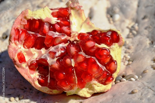 Obraz na plátně A ripe red sliced ​​pomegranate and granate grains lie on a white stone