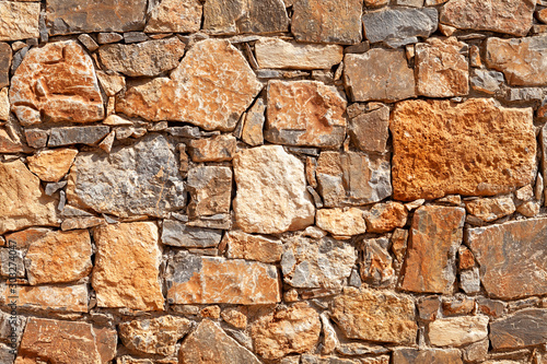 old stone wall of stones of different shapes,