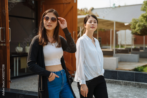Two asian japanese women friends walking along road on sunny day. elegant young ladies travelers out from a wooden vintage house and keep sightseeing little village in tokyo japan. stylish female © PR Image Factory