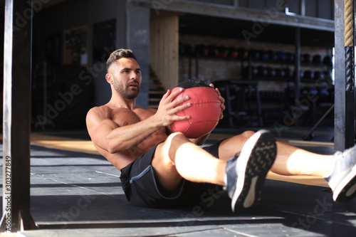 Fit and muscular man exercising with medicine ball at gym.