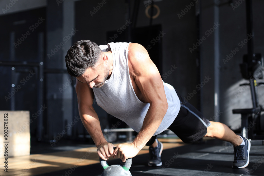 Fit and muscular man focused on lifting a dumbbell during an exercise class in a gym. Fit and muscular man focused on lifting a dumbbell during an exercise class in a gym.