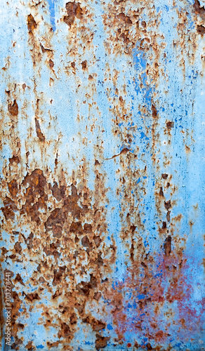 A section of a rusty, corroded, and worn steel sliding gate in front of a residential community.