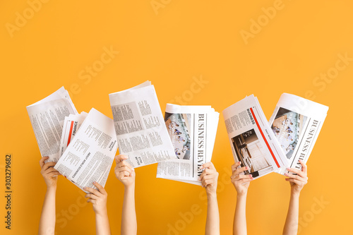 Female hands with newspapers on color background photo