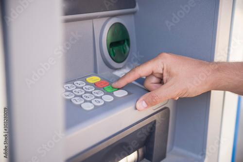Hand entering personal identification number on ATM dial panel photo