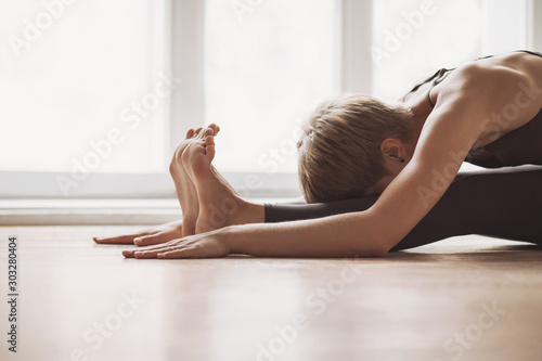 Young woman practicing yoga at class, working out, wearing sportswear, indoor, home interior background. Harmony, balance, meditation, relaxation, healthy lifestyle concept