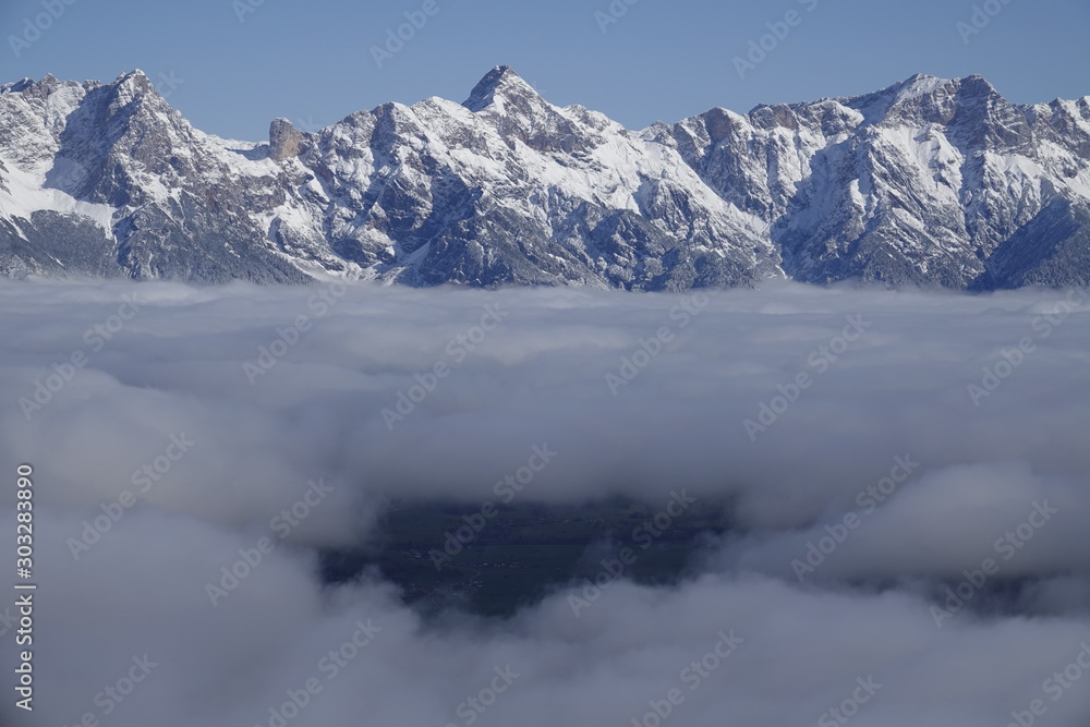 beautiful view to the snow capped mountains in austria with snowed in trees and a misty valley